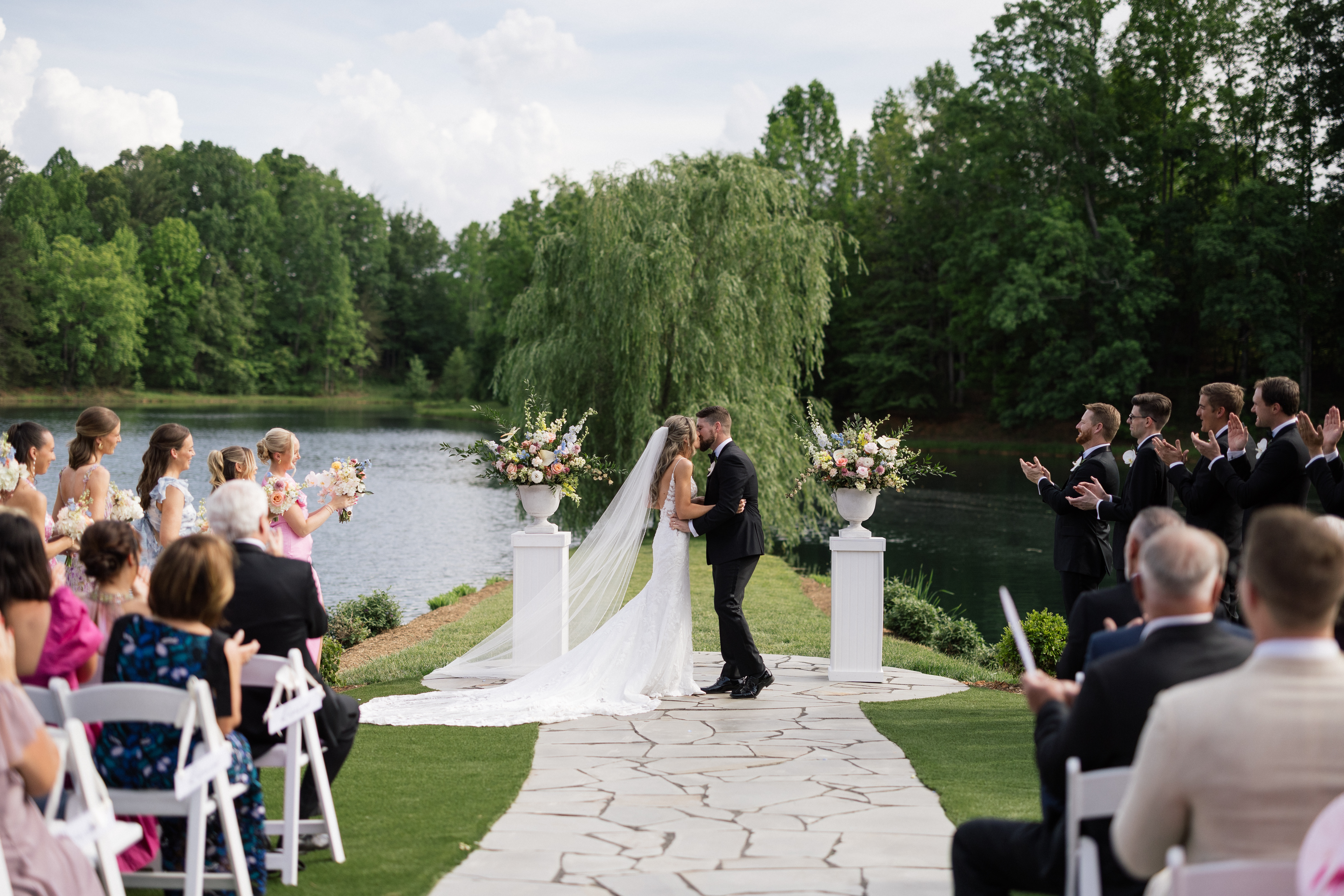 The Peninsula — ceremony by pond with willow tree and floral arbor
